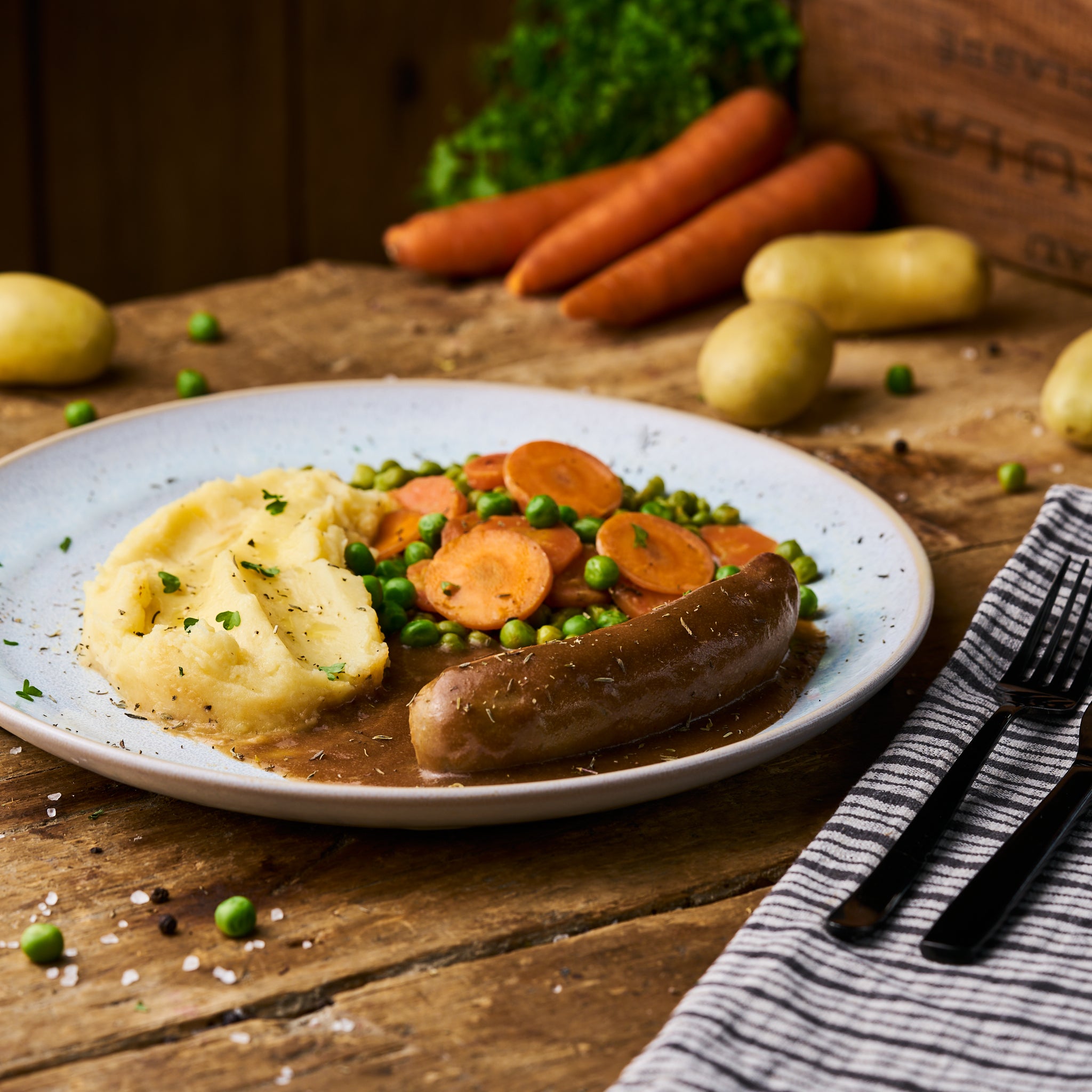 Bratwurst in Sauce an Erbsen-Möhrengemüse und Kartoffelstampf