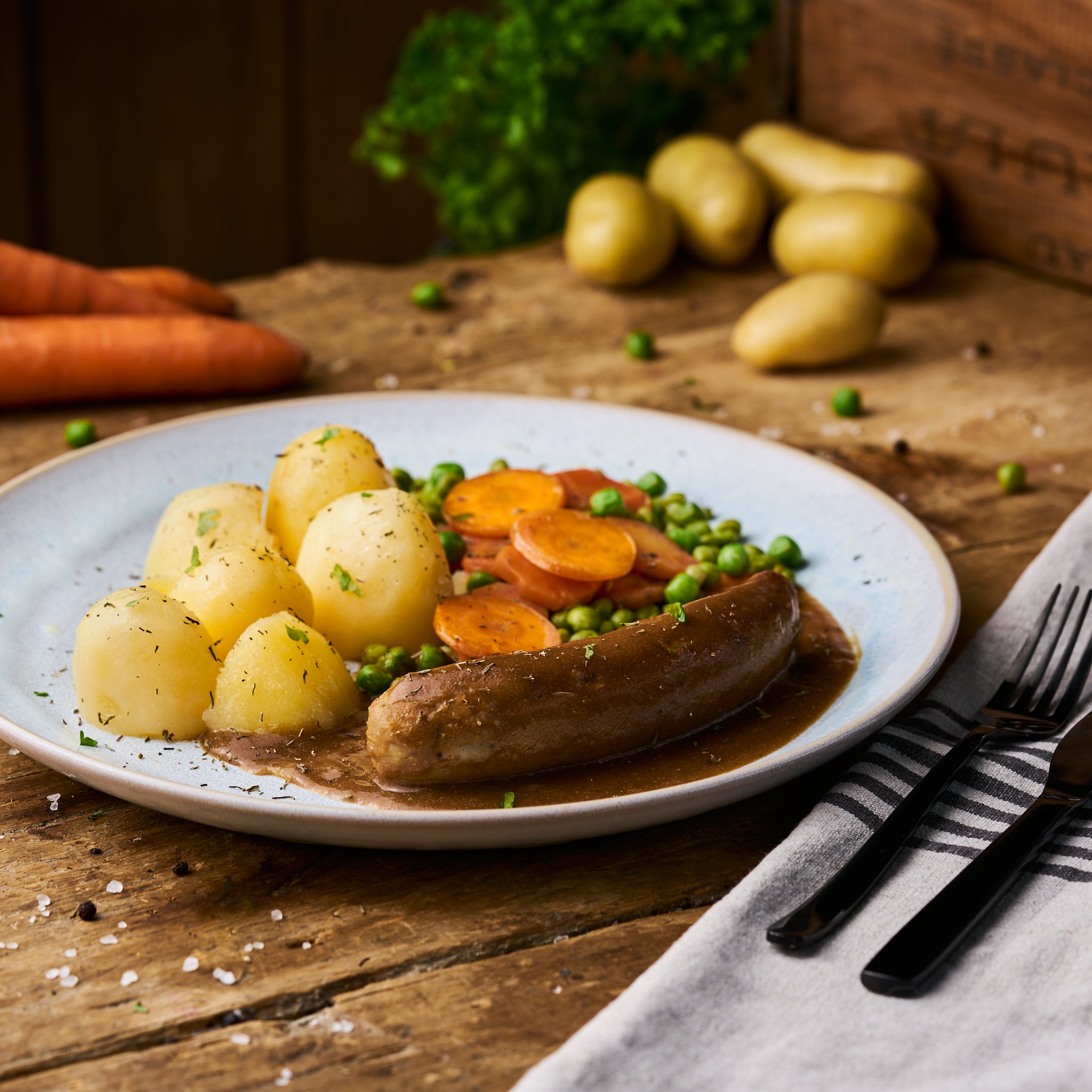 Bratwurst in Sauce an Erbsen-Möhrengemüse und Butterkartoffeln